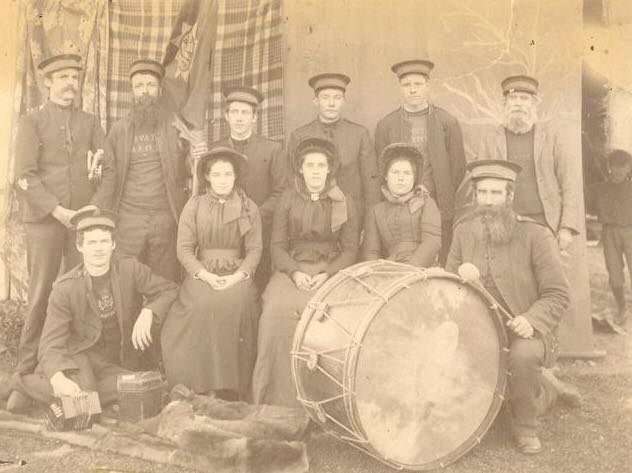 A late-nineteenth-century Salvation Army Corps photograph — soldiers, officers, bandsmen, the bass drum, the concertina, the flag